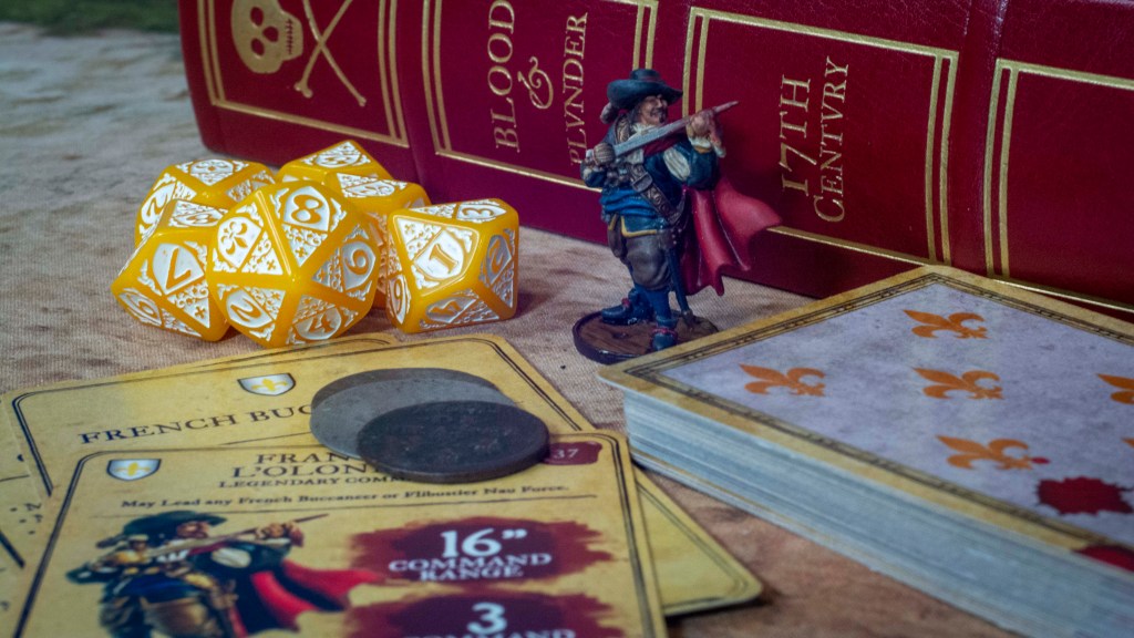 Blood & Plunder French Faction collage with dice, miniatures, cards, coins and the rulebook