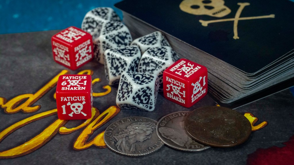 Blood & Plunder Fatigue Dice, d10 dice, coins, and cards on top of the rulebook